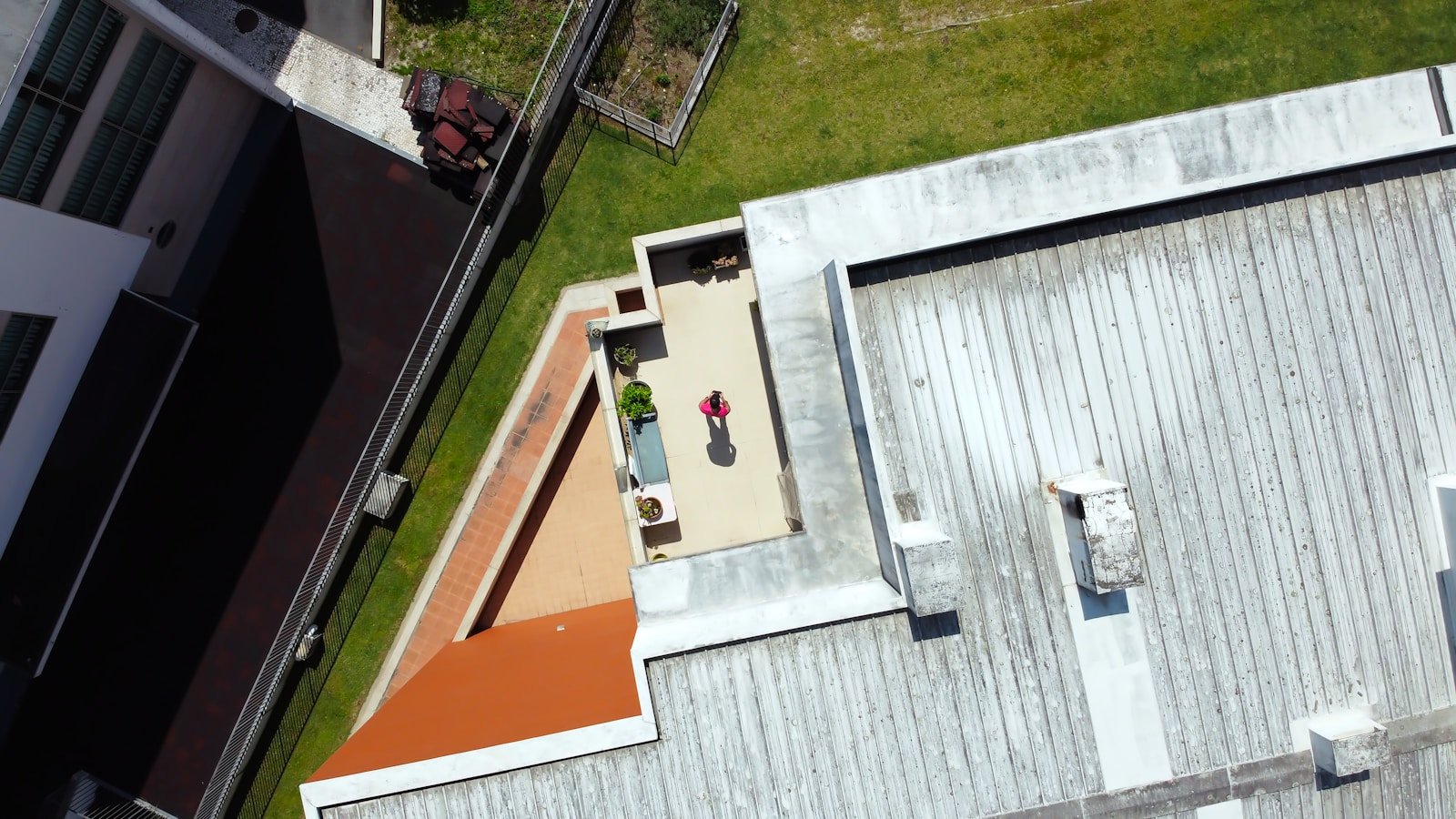 man in yellow shirt and blue denim jeans standing on white concrete building during daytime